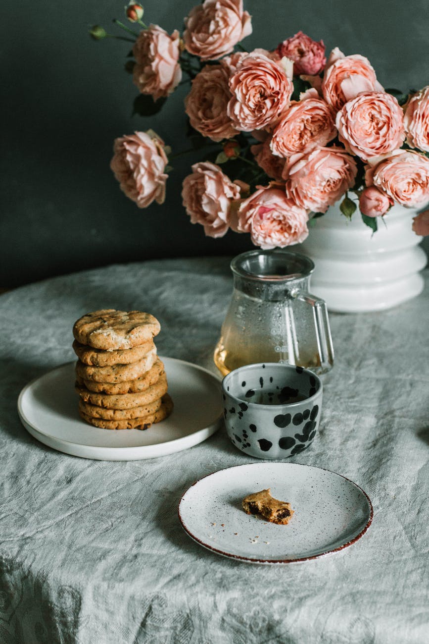 pink flowers beside plate of biscuits